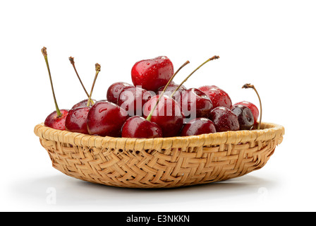 Un mucchio di rosso fresco e naturale di ciliege in un cesto in rattan. Foto Stock