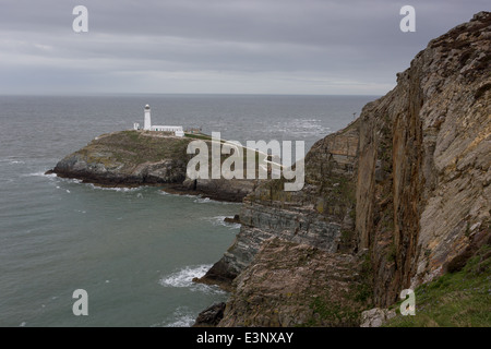 A sud della pila, una piccola isola con un faro appena fuori a Isola Santa sulla costa nord occidentale di Anglesey. Foto Stock