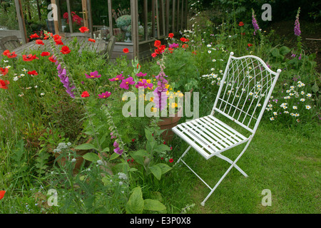 Grazioso giardino di fiori e giardino con sedile trug e attrezzi Foto Stock