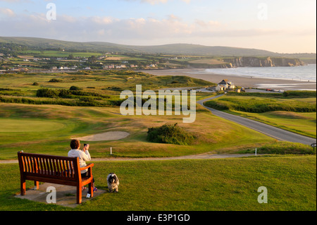 Newport Links Golf Club, donna su banco affacciato sulla spiaggia di Newport Pembrokeshire, Wales, Regno Unito Foto Stock