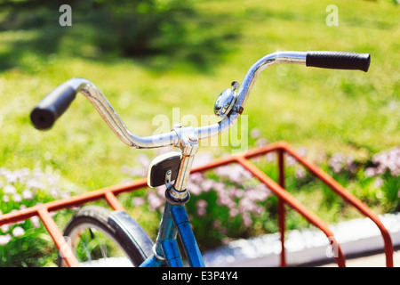 Vintage manubrio di bicicletta dettaglio chiudere con parcheggio sfondo bokeh di fondo nel letto di fiori in giornata soleggiata Foto Stock