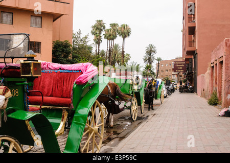 Carrozze trainate da cavalli parcheggiato in una strada di Marrakech, Marocco. Turisti spesso imbrogliati da non concordare il prezzo in anticipo. Foto Stock