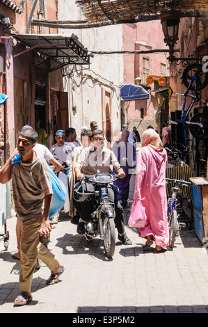 Un sacco di persone in vari modi di trasporto percorrendo una strada stretta nella Medina di Marrakech, Marocco Foto Stock