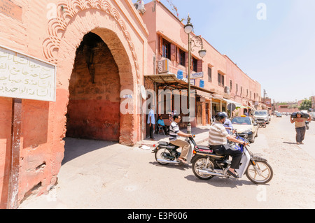 La gente ride scooter fuori di uno dei 20 porte attraverso le mura che circondano la Medina, Marrakech, Marocco Foto Stock