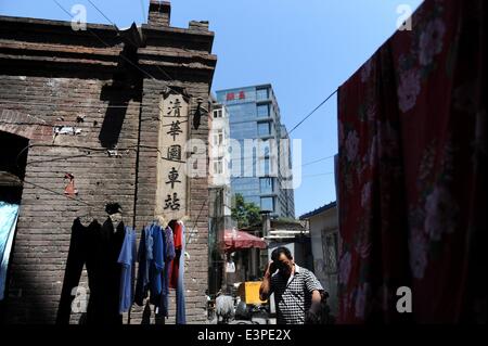 (140626) -- Pechino, 26 giugno 2014 (Xinhua) -- Un residente passeggiate passato il cartello della Vecchia Università Tsinghua Station su Wudaokou nel Distretto Haidian di Pechino, capitale della Cina, 22 giugno 2014. Wudaokou, letteralmente in cinese il quinto passaggio a livello dell'Beijing-Baotou Raiwaly, è un quartiere del Distretto Haidian del nord ovest di Pechino. In prossimità di un gran numero di università e noto per la sua grande numero di studenti internazionali, Wudaokou ha un altro nome 'Universo Center' circolanti tra gli studenti universitari. La vecchia Università Tsinghua stazione ferroviaria, che era stato costruito nel 1910 Foto Stock