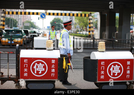 (140626) -- Pechino, 26 giugno 2014 (Xinhua) -- poliziotti ferroviari di trasporto di blocco in corrispondenza di un incrocio di mantenere la sicurezza il passaggio di un treno su Wudaokou nel Distretto Haidian di Pechino, capitale della Cina, 13 giugno 2014. Wudaokou, letteralmente in cinese il quinto passaggio a livello dell'Beijing-Baotou Raiwaly, è un quartiere del Distretto Haidian del nord ovest di Pechino. In prossimità di un gran numero di università e noto per la sua grande numero di studenti internazionali, Wudaokou ha un altro nome 'Universo Center' circolanti tra gli studenti universitari. La vecchia Università Tsinghua stazione ferroviaria, che Foto Stock