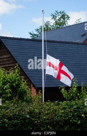 Una bandiera inglese (il St George's Cross) vola a metà del montante in Inghilterra dopo la sconfitta nel 2014 Coppa del Mondo di Calcio Foto Stock