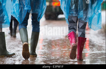 Stivali in gomma sono visti a piedi attraverso i campi fangosi di azienda agricola degna durante il 2014 Festival di Glastonbury nel Somerset, Giugno 2014. Foto Stock