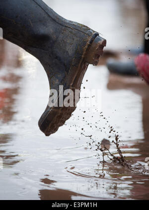 Stivali in gomma sono visti a piedi attraverso i campi fangosi di azienda agricola degna durante il 2014 Festival di Glastonbury nel Somerset, Giugno 2014. Foto Stock