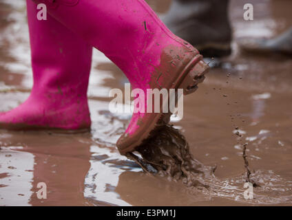 Stivali in gomma sono visti a piedi attraverso i campi fangosi di azienda agricola degna durante il 2014 Festival di Glastonbury nel Somerset, Giugno 2014. Foto Stock