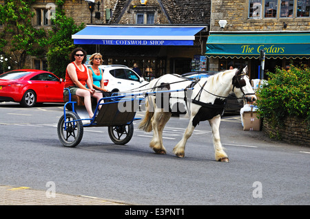 I turisti facendo un giro in un cavallo e trappola attorno al villaggio, Bourton sull'acqua, Inghilterra, Regno Unito. Foto Stock