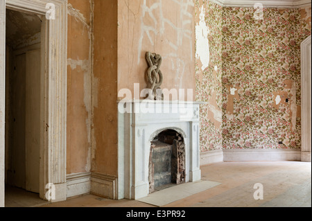 Vecchio murate caminetto in camera a vuoto con la carta da parati si stava staccando e pavimenti non levigata Foto Stock