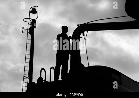 Il vigile del fuoco di un treno a vapore il riempimento con acqua. Foto Stock