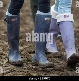 Stivali in gomma sono visti a piedi attraverso i campi fangosi di azienda agricola degna durante il 2014 Festival di Glastonbury nel Somerset, Giugno 2014. Foto Stock