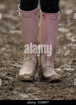 Stivali in gomma sono visti a piedi attraverso i campi fangosi di azienda agricola degna durante il 2014 Festival di Glastonbury nel Somerset, Giugno 2014. Foto Stock