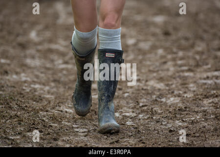 Stivali in gomma sono visti a piedi attraverso i campi fangosi di azienda agricola degna durante il 2014 Festival di Glastonbury nel Somerset, Giugno 2014. Foto Stock