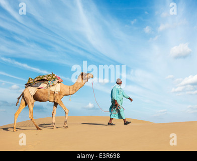 Rajasthan travel background - cameleer indiano (camel driver) con i cammelli in dune del deserto di Thar. Jaisalmer, Rajasthan, India Foto Stock