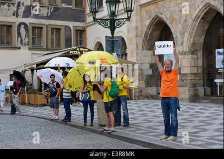 Un gruppo di persone che offrono i loro servizi come guida per i turisti in Piazza della Città Vecchia di Praga, Repubblica Ceca. Foto Stock