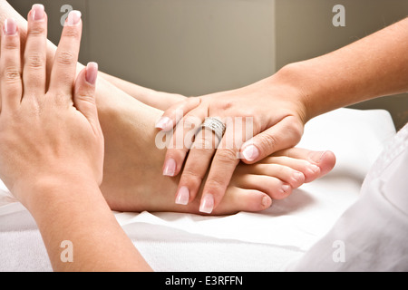 Donna con le mani in mano dando un sano massaggio ai piedi Foto Stock