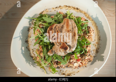 Pollo con riso selvatico insalata, tra cui pomodori seccati al sole il formaggio feta, rucola, cipolline, il coriandolo e il cetriolo. Foto Stock