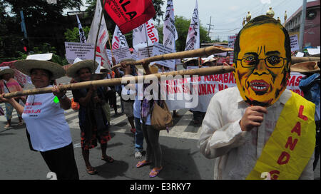 Manila, Filippine. Il 27 giugno, 2014. MANILA, Filippine - i dimostranti mockingly spinta germogli di bambù per un uomo che indossa il presidente filippino Aquino la maschera come agricoltori a partire dalla controversa zucchero station wagon Hacienda Luisita, come pure i manifestanti da differenti militante e gruppi di lavoro fase simultaneamente una protesta presso lo storico ponte Mendiola appena fuori dalle porte del Palazzo Presidenziale a Manila il 27 giugno 2014. Credito: ZUMA Press, Inc./Alamy Live News Foto Stock