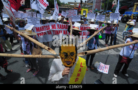 Manila, Filippine. Il 27 giugno, 2014. MANILA, Filippine - i dimostranti mockingly spinta germogli di bambù per un uomo che indossa il presidente filippino Aquino la maschera come agricoltori a partire dalla controversa zucchero station wagon Hacienda Luisita, come pure i manifestanti da differenti militante e gruppi di lavoro fase simultaneamente una protesta presso lo storico ponte Mendiola appena fuori dalle porte del Palazzo Presidenziale a Manila il 27 giugno 2014. Credito: ZUMA Press, Inc./Alamy Live News Foto Stock