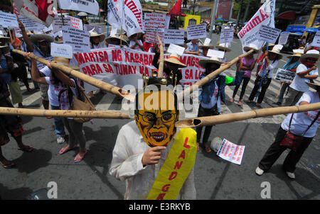 Manila, Filippine. Il 27 giugno, 2014. MANILA, Filippine - i dimostranti mockingly spinta germogli di bambù per un uomo che indossa il presidente filippino Aquino la maschera come agricoltori a partire dalla controversa zucchero station wagon Hacienda Luisita, come pure i manifestanti da differenti militante e gruppi di lavoro fase simultaneamente una protesta presso lo storico ponte Mendiola appena fuori dalle porte del Palazzo Presidenziale a Manila il 27 giugno 2014. Credito: ZUMA Press, Inc./Alamy Live News Foto Stock