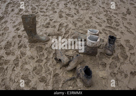 Stivali in gomma sono visti a piedi attraverso i campi fangosi di azienda agricola degna durante il 2014 Festival di Glastonbury nel Somerset, Giugno 2014. Foto Stock