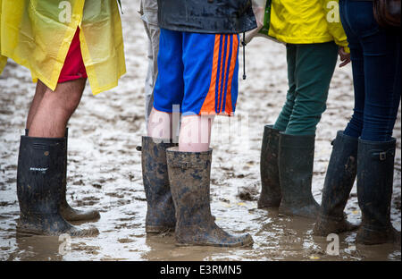 Stivali in gomma sono visti a piedi attraverso i campi fangosi di azienda agricola degna durante il 2014 Festival di Glastonbury nel Somerset, Giugno 2014. Foto Stock