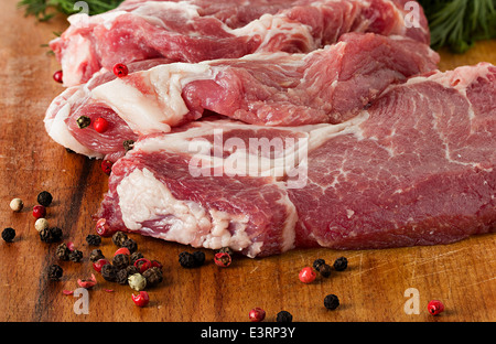 Materie bistecca di carne di maiale al buio su un tavolo di legno Foto Stock