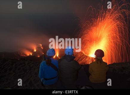 I turisti con i caschi guardando eruzione vulcanica al vulcano Stromboli, Isole Eolie, di notte Foto Stock