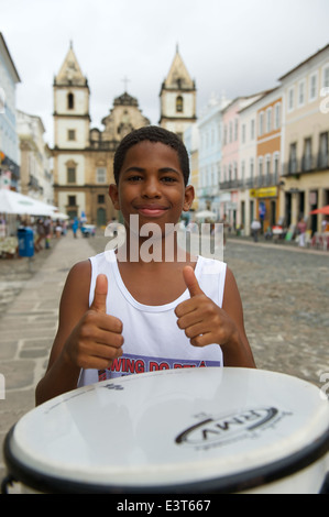 SALVADOR, Brasile - 15 ottobre 2013: giovane brasiliano sta pollice in alto con un tamburo nel centro storico di Pelourinho. Foto Stock