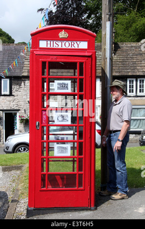 Tourist la lettura di un poema su un convertito casella telefono nel Derbyshire villaggio di Tideswell Foto Stock