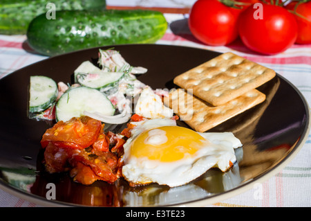 Uovo fritto con pomodori per la prima colazione. Insalata di verdure. Foto Stock