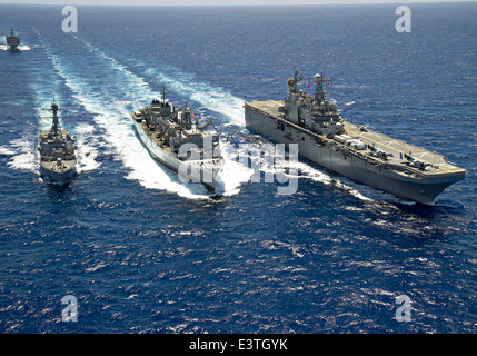 US Navy Amphibious Assault nave USS Peleliu e Arleigh Burke-class missile destroyer USS Spruance durante un rifornimento in mare con Sealift militare il comando rapido supporto di combattimento nave USNS Ranieri durante gli esercizi RIMPAC Giugno 24, 2014 al largo delle Hawaii. Foto Stock