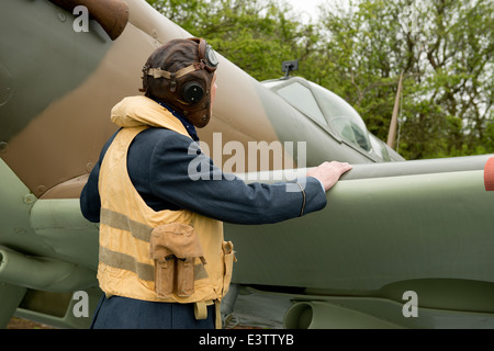 WW2 RAF pilota, indossa il suo Mae West giubbotto di salvataggio, ispeziona il suo Spitfire Fighter Aircraft per eventuali segni di danneggiamento. Foto Stock