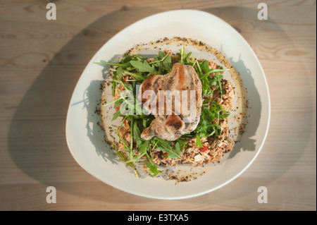 Pollo con riso selvatico insalata, tra cui pomodori seccati al sole il formaggio feta, rucola, cipolline, il coriandolo e il cetriolo. Foto Stock