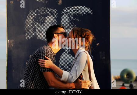 Brighton, Sussex, Regno Unito. Il 29 giugno, 2014. Un paio di rubare un bacio da baciare la statua sul lungomare di Brighton Foto Stock