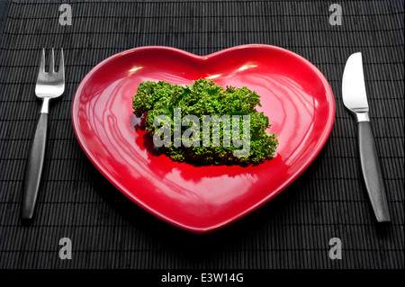 Concetto di cavolo riccio mangiare sano regime con cuore piastra sagomata e Kale porzione di vegetali Foto Stock