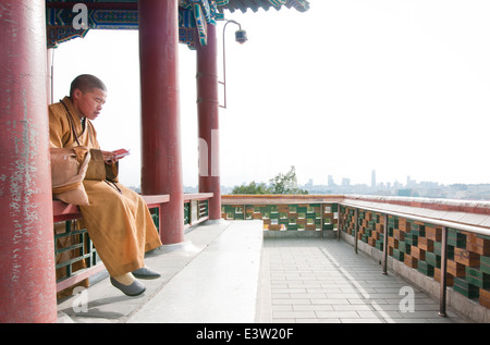 Giovane monaco buddista pregando in Wanchun ting Pavilion (Padiglione dell'eterna primavera) nel Parco Jingshan, Pechino, Cina Foto Stock