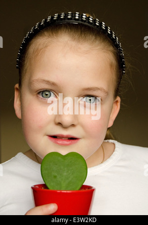 Giovane ragazza tenendo un Hoya Kerrii a forma di cuore di piante in vaso Foto Stock