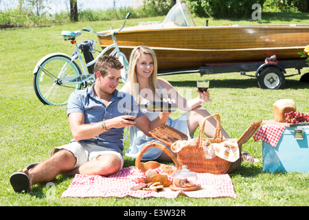 Un giovane gode di un picnic estivo dal lago in una impostazione paese Foto Stock