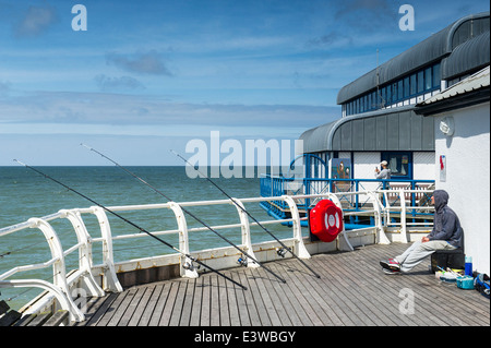 Un pescatore che pesca al largo Cromer Pier. Foto Stock