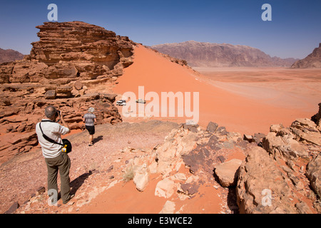 Giordania, Wadi Rum, i turisti occidentali la visualizzazione di dune di sabbia rossa dal promontorio roccioso Foto Stock