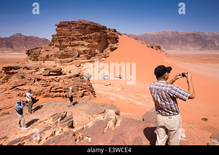 Giordania, Wadi Rum, i turisti occidentali la visualizzazione di dune di sabbia rossa dal promontorio roccioso Foto Stock