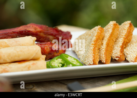 Cucina cinese antipasti su un vassoio esterno, compresi involtini primavera, nervature e di sesamo boreale su pane tostato Foto Stock
