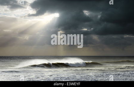 Bellissimo paesaggio marino con luminosi raggi del sole e di nuvole scure su un mare ondeggiante Foto Stock