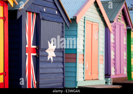 Cabine sulla spiaggia, a Melbourne la spiaggia di Brighton Australia con colorate bandiera australiana dipinta su in estate sun. Foto Stock