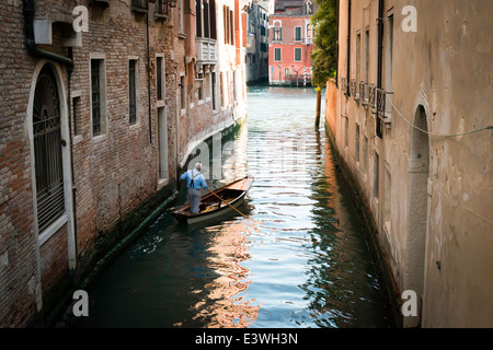 Un uomo su una barca a Venezia. Pass-thru il canale Foto Stock