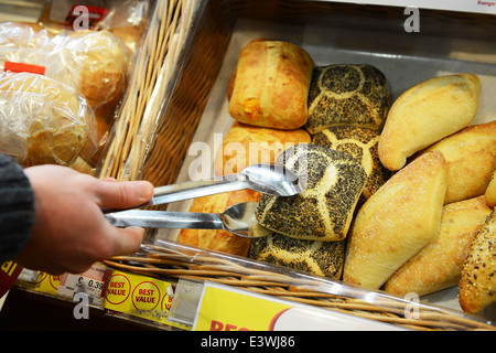 Un cliente selezionando un rotolo di pane in un supermercato Foto Stock